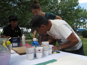 A gardener paints his sign with support from Carmen Bouyer. Photo by, Elizabeth Gilcrest, LOR Community Organizer